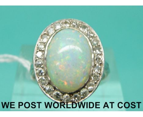 An Art Deco 18ct white gold ring set with an oval opal cabochon surrounded by diamonds (size L)