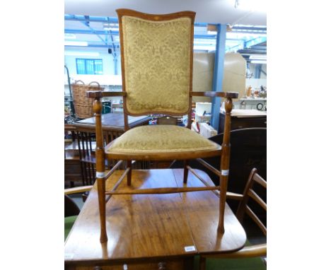An Edwardian upholstered mahogany armchair with inlaid surround, shaped arms and tapered turned legs