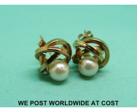 A pair of 9ct gold earrings in a knot design set with a pearl