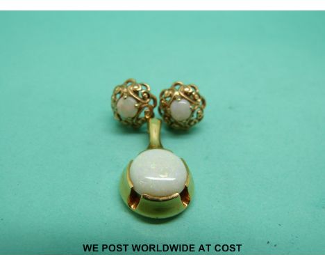 A 14ct gold pendant set with an opal cabochon and a pair of 9ct gold earrings set with opals