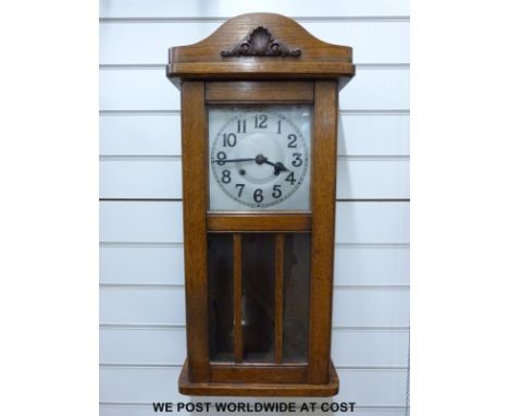 A c1910 light oak cased English wall clock, Arabic numerals on metal dial, large spade hands, the movement striking on a gong