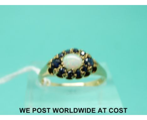 A 9ct gold ring set with an opal surrounded by sapphires (size N)