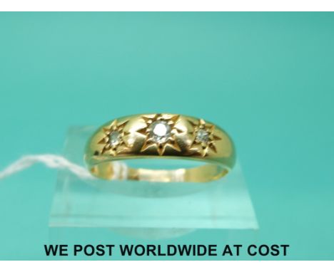 A yellow metal ring marked 18ct set with three diamonds in a star setting (size N)