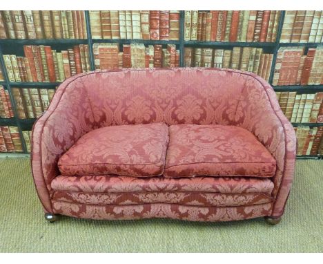 A 19th/20thC two seater burgundy upholstered sofa on oak bun feet and metal castors 