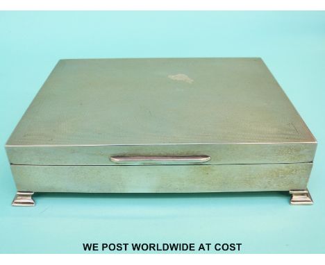A large engine turned hallmarked silver cigarette case raised on four feet, Birmingham 1955, width 18cm