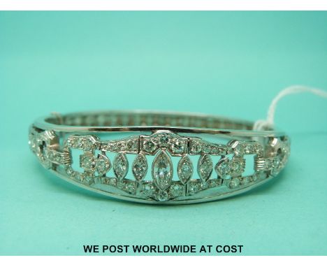 A white metal bangle set with a marquise cut diamonds surrounded by round cut diamonds in a buckle design. 
