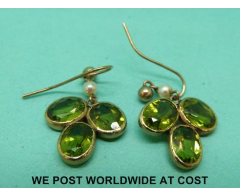 A pair of 9ct gold earrings set with peridots and a pearl to each 