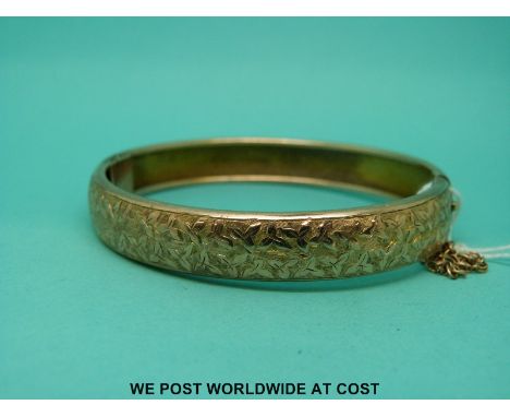 A 9ct gold bangle with engraved foliate design (12.6g)