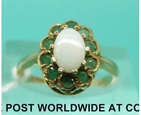 A 9ct gold ring set with an opal surrounded by emeralds (size K)