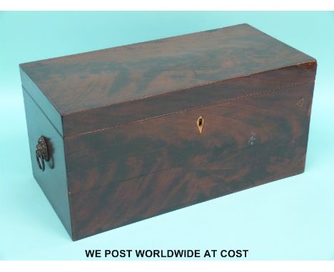 A Georgian flame mahogany tea caddy with lion mask handles, opening to reveal two lidded compartments flanking central mixing