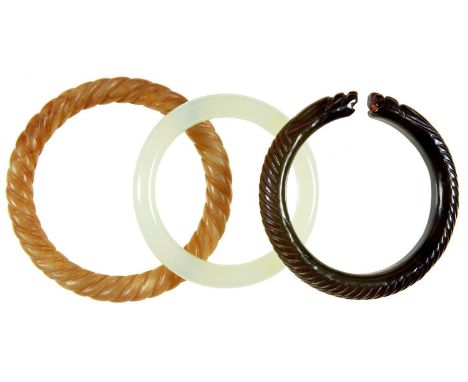 A JADE BANGLE, 73MM DIAM AND TWO OTHER CARVED HARDSTONE BANGLES (3)Condition report  Good condition