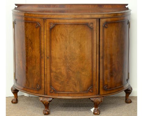A SEMI ELLIPTICAL WALNUT COMMODE, C1930, IN GEORGE III STYLE, WITH BUTTERFLY VENEERED TOP AND THREE DOORS, ON DWARF CABRIOLE 