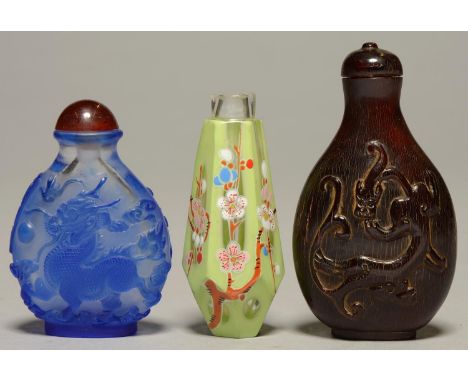 THREE CHINESE SNUFF BOTTLES, COMPRISING BLUE OVERLAY GLASS CARVED WITH A QILIN, TAPERED HEXAGONAL CASED GLASS AND FLORAL ENAM
