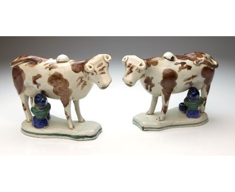 A pair of 19th century, possibly Scottish, pottery cow and milk maid creamers, with ochre, mid blue and copper green enamel d