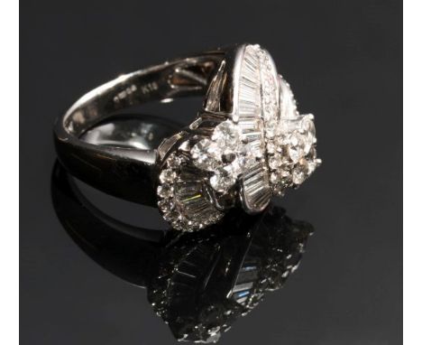 A diamond set cross-over dress ring, with two scrolling bands of graduated baguette diamonds terminating in four stone brilli