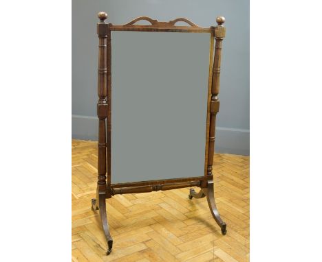 A George IV mahogany cheval mirror, having a pierced serpentine rail above a plain rectangular plate within ring turned and b