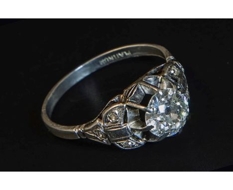 A single stone diamond ring, the old brilliant cut diamond in raised claw mount, with carved diamond set shoulders and plain 