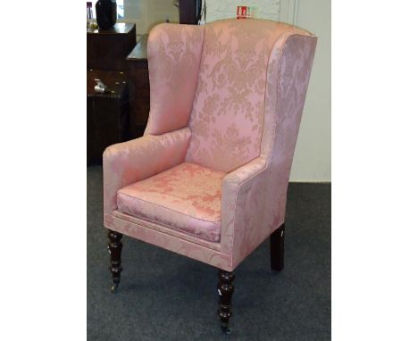 A Victorian deep wing back armchair, adapted as a commode, later upholstered in flowering basket embroidered salmon pink, on 