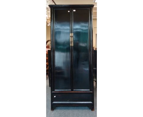 A Chinese black lacquer painted robe cupboard, having a moulded cornice over a pair of panel doors, with steel furniture encl