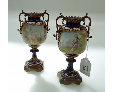 A pair of 19th century Sevres bleu de Roi porcelain, gilded and ormolu mounted twin handled pedestal urns, decorated with a f