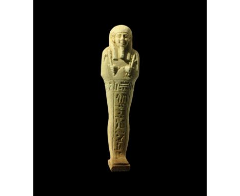 Late Period, 664-332 BC. A pale green finely modelled glazed composition shabti with tripartite wig, false beard, agricultura