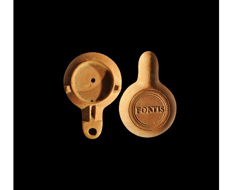 Late 1st century AD. A terracotta factory oil lamp with lugs to the shoulder, recessed discus, nozzle with chamfered sides, c