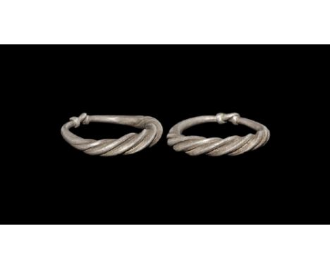 9th-11th century AD. A round-section silver hoop with tapering ends coiled around the shank, bezel formed as three twisted wi