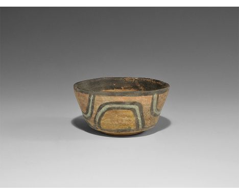 3300-1300 BC. A squat ceramic cup with basal disc, flared sidewall, black rim and outlines to band of green-blue loops in vib