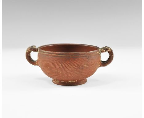 2nd century AD. A two handled ceramic cup with incised rope pattern to the body and pelta shaped ends to the handles. Propert