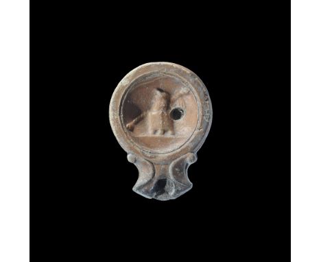 1st century AD. A terracotta lamp with short nozzle and scrolled shoulders, discus with recess and high-relief imperial bust 