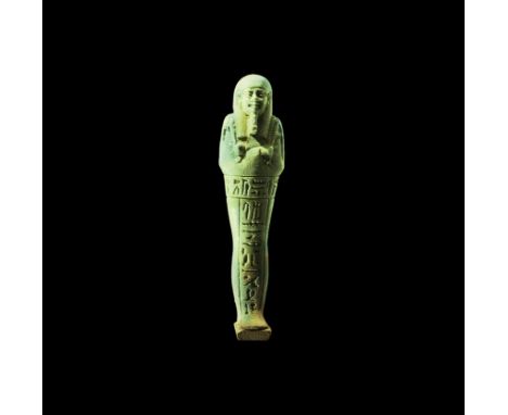 Late Period, 664-332 BC. A pale green finely modelled glazed composition shabti with tripartite wig, false beard, agricultura