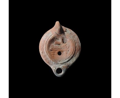 2nd-3rd century AD. A small terracotta oil lamp with loop handle to the rear, short nozzle, concentric rings to the discus, l
