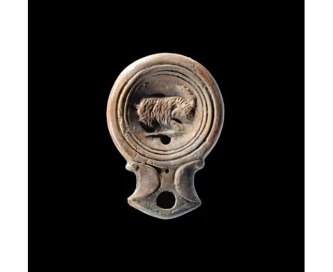 Late 1st-early 2nd century AD. A terracotta oil lamp with broad nozzle, scrolled shoulders, concentric rings to the discus, h