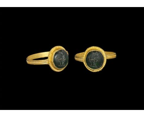 3rd-4th century AD. A flat-section gold hoop with median beaded band, discoid plaque with cell and beaded border, inset green