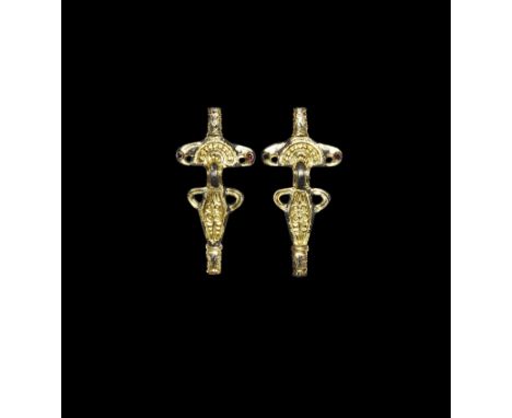 6th century AD. A matched pair of silver-gilt bow brooches, each a D-shaped headplate with beaded arc and nicked outer edge, 