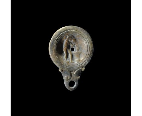 2nd century AD. A squat terracotta oil lamp with broad nozzle and scrolled shoulders, concentric rings to the discus and low-
