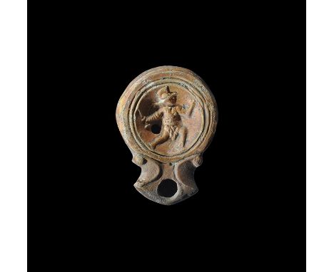 Early 1st century AD. A small terracotta lamp with short nozzle and broad scrolled shoulders, three concentric rings to the d