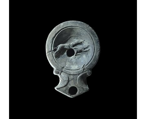 1st-2nd century AD. An ornamented terracotta lamp with volute scrolls to the nozzle; to the discus a running dog chasing a ha