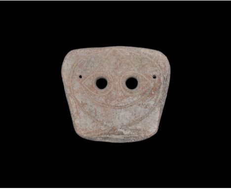 4th-3rd century BC. A trapezoidal slightly curved ceramic mask with two eye-holes and incised stylised facial details; pierce