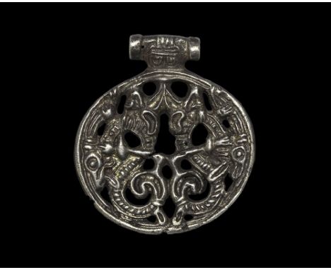 900-950 AD. A silver openwork discoid pendant with integral T-shaped tubular loop; raised gussetted rim enclosing a pair of S