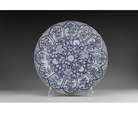 Kangxi Period, Late 17th century AD. A blue and white glazed ceramic lotus charger with barbed rim, central dense chrysanthem