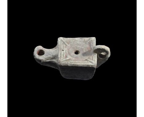 1st century AD. A terracotta oil lamp, cuboid in form with pierced lug handle to the rear, short nozzle, raised bans to the u