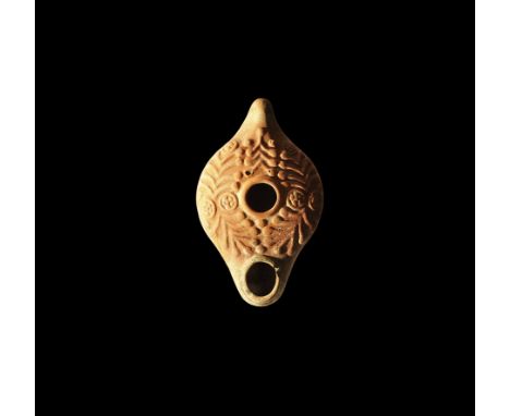 5th century AD. A large terracotta oil lamp with stub handle to the rear, bulbous nozzle, high-relief foliage and roundel flo