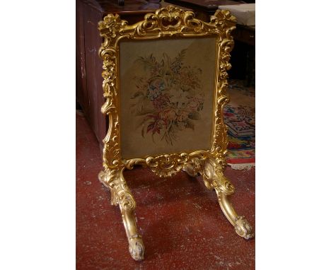 A Victorian carved gilt decorated firescreen inset with floral needlework 