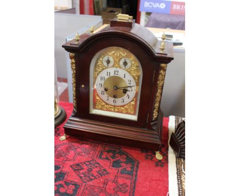A modern mahogany domed bracket clock with ormolu mounts, pineapple finials and lions paw feet, brass face with two subsidiar