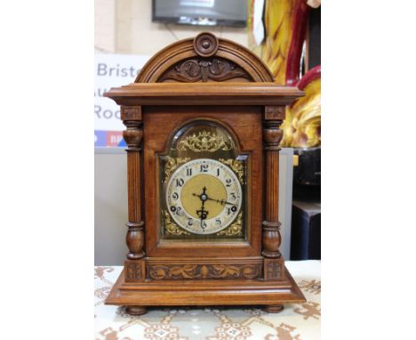 A modern walnut domed bracket clock with ormolu face and Arabic numeral markers.