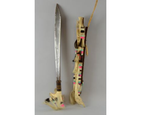 Borneo Dayak parang Ilang with carved bone handle and angled blade in reed scabbard with bone carving, decorated with multi c