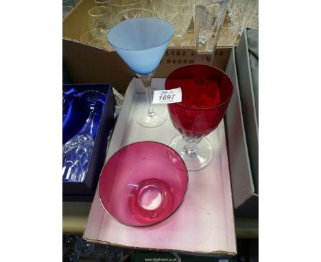 A cranberry glass sugar bowl, red glass goblet, a blue cocktail glass and a clear studio candlestick.