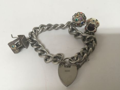 A silver charm bracelet with three charms and a padlock clasp.