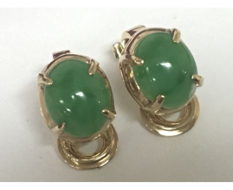 A pair of high grade gold clip on earrings set with green jade cabochon weight approximately 4g unmarked.